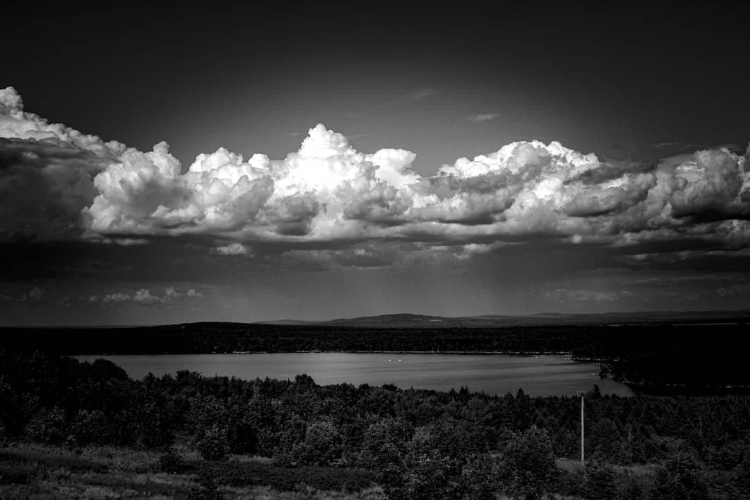 A black and white photo of clouds over a lake