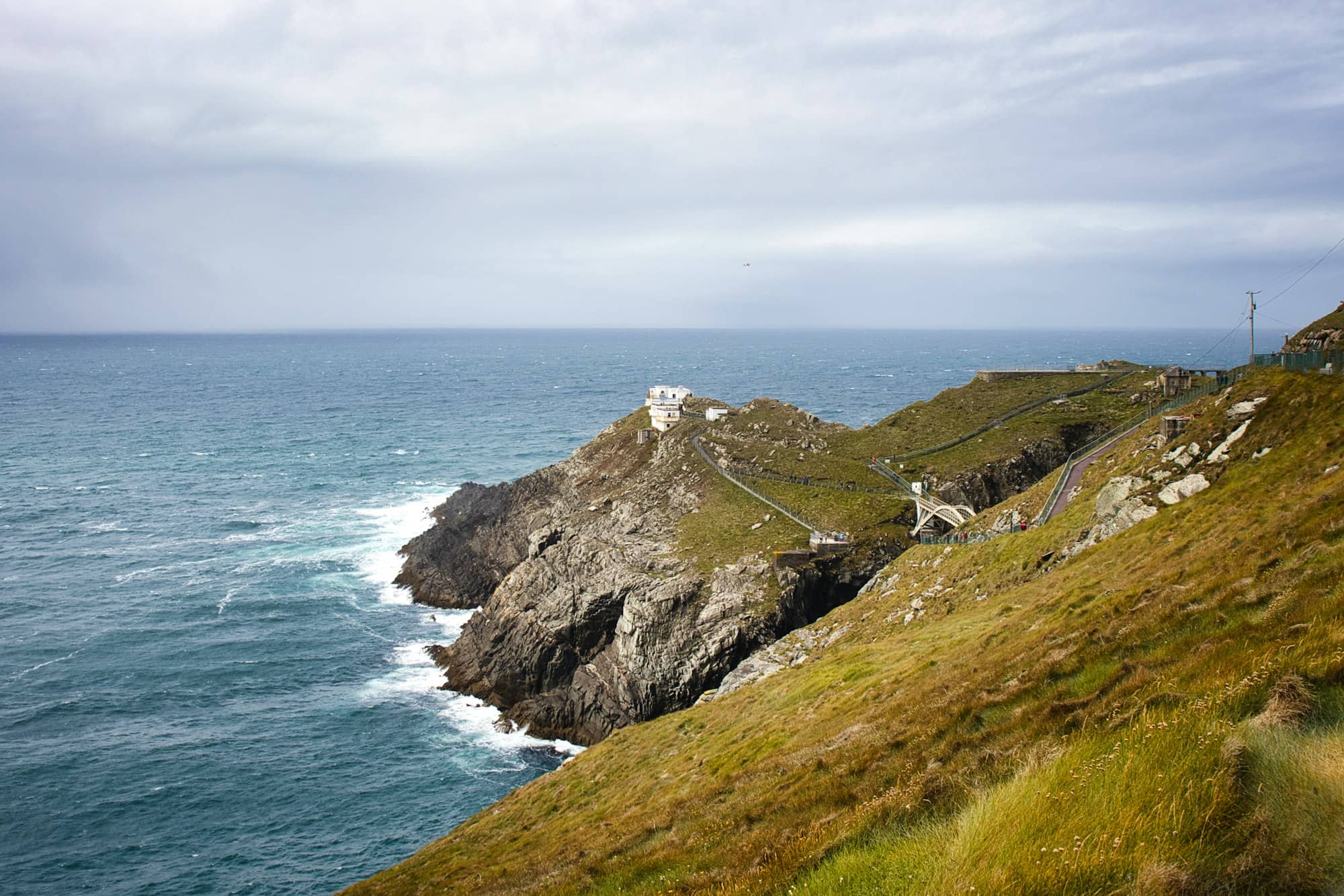 Rugged coastline with a lighthouse under cloudy sky