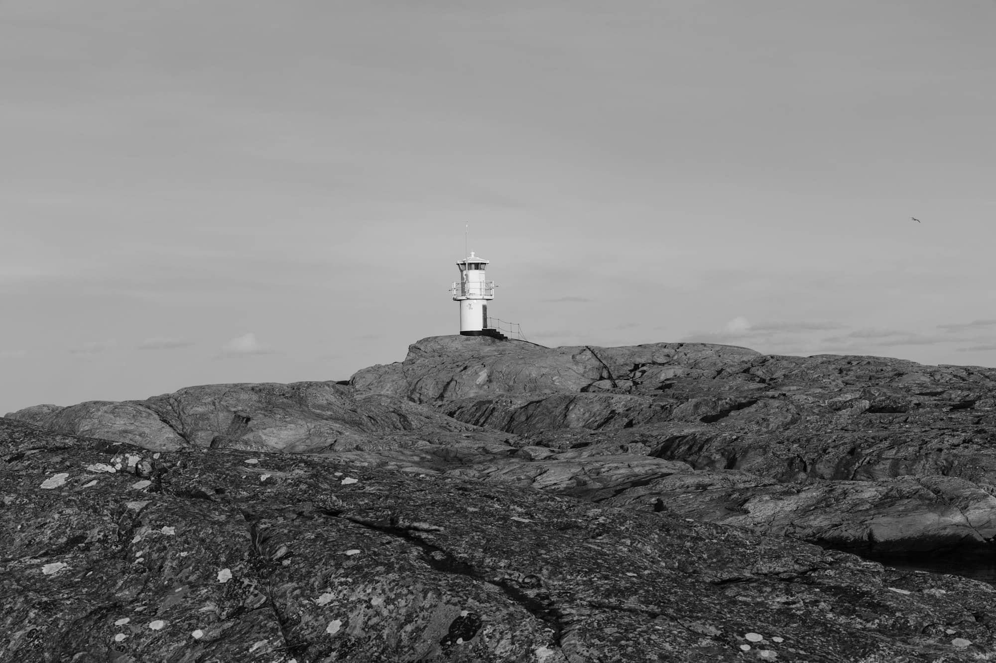A black and white photo of a lighthouse on a rock