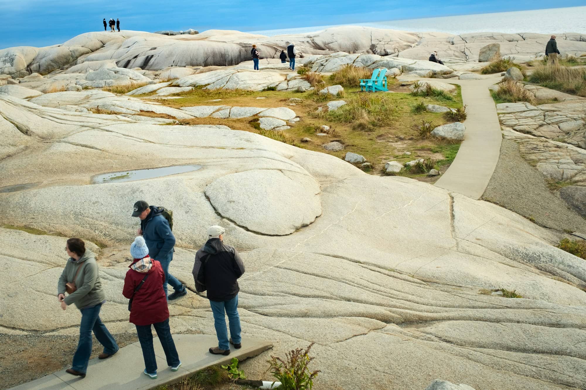 People walk on a rocky coastline with a path.