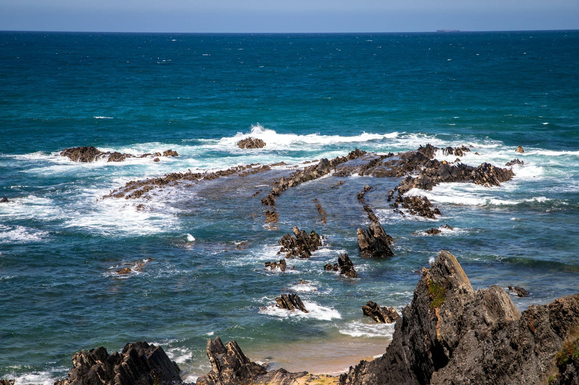 Waves crash against rugged coastal rock formations.