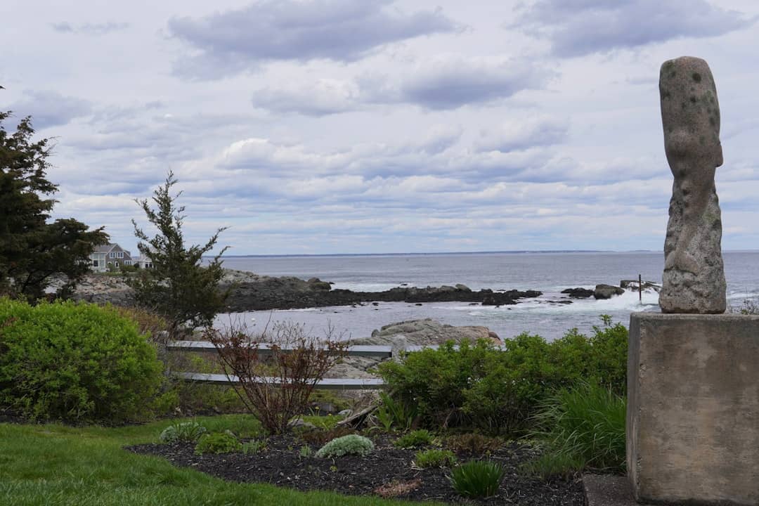 A stone sculpture overlooks the ocean under a cloudy sky.