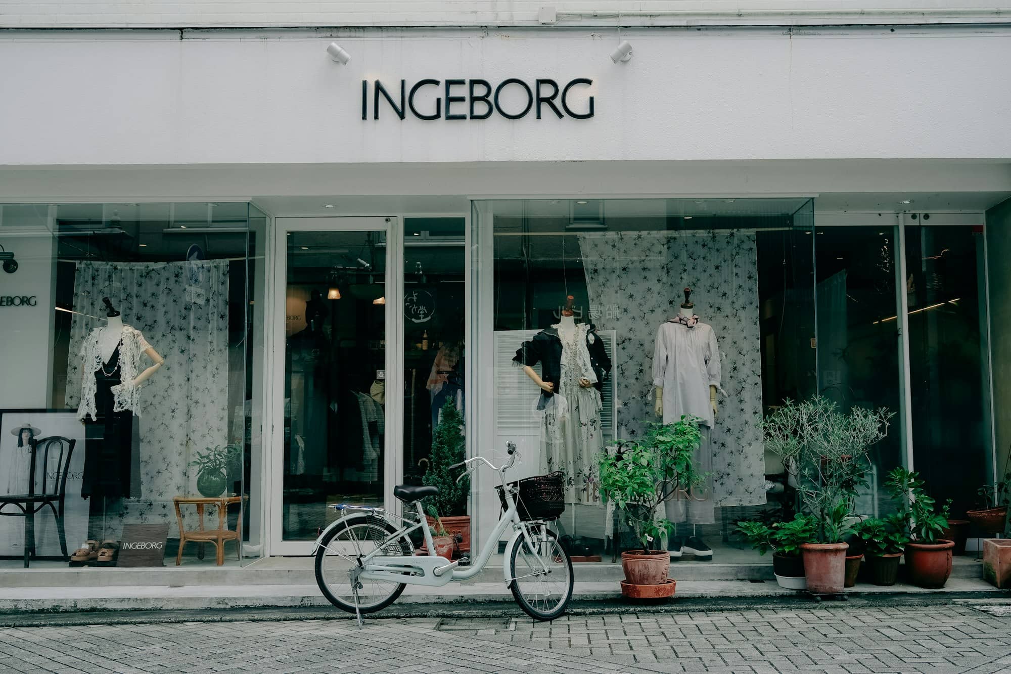 Bicycle parked outside a storefront with mannequins.