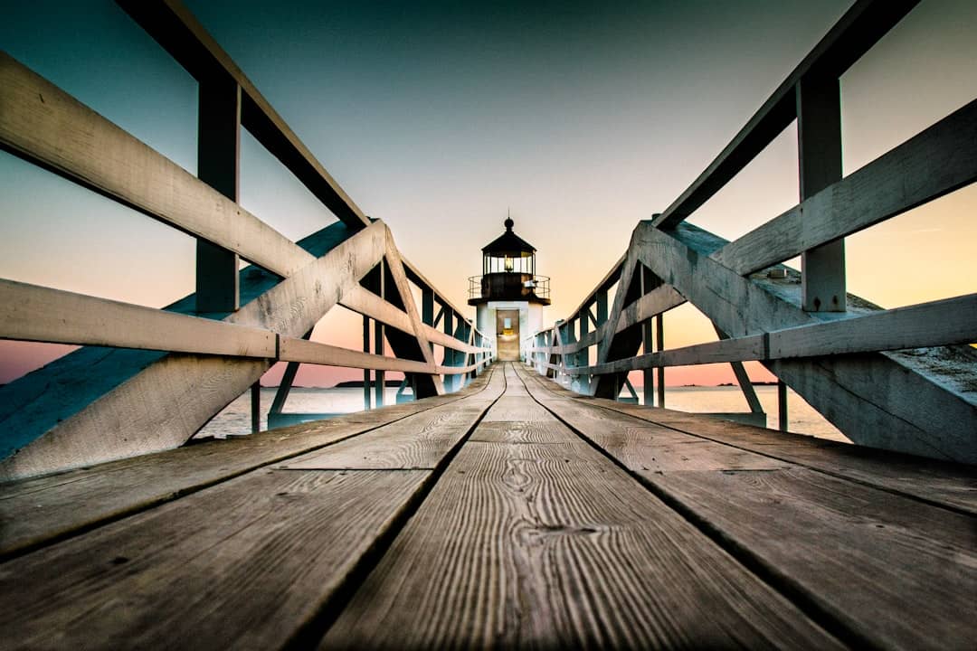a wooden pier with a light house in the background