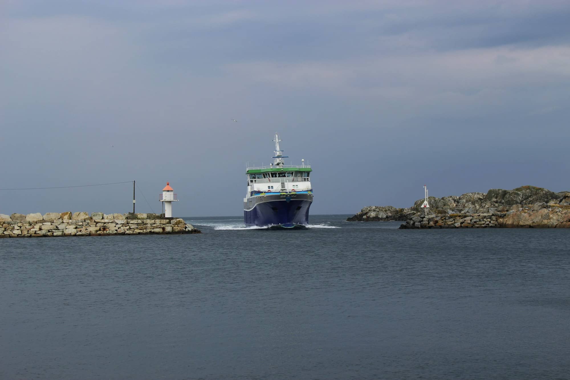 green and white ship on sea under gray sky during daytime