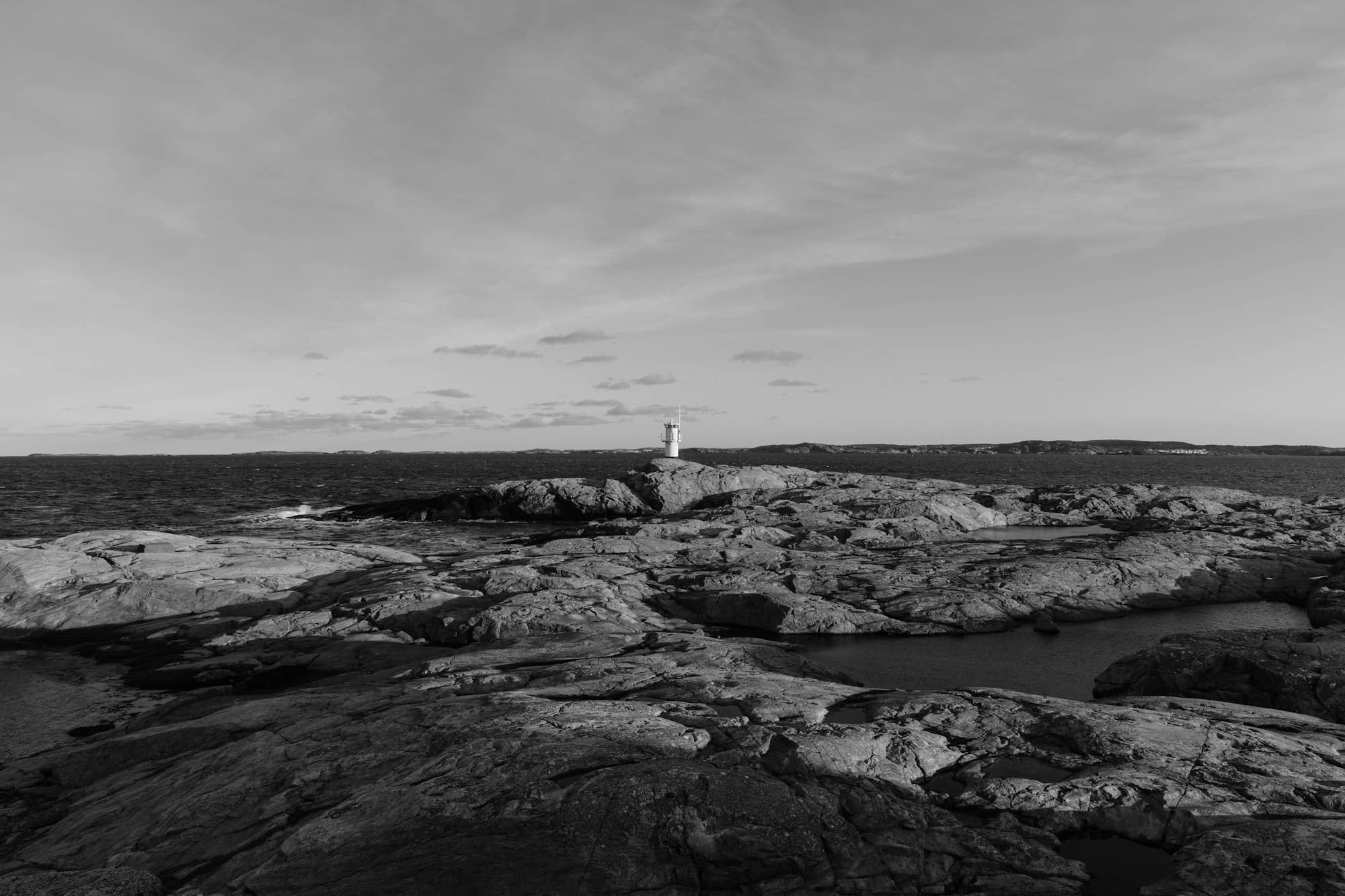A black and white photo of a lighthouse on a rocky shore