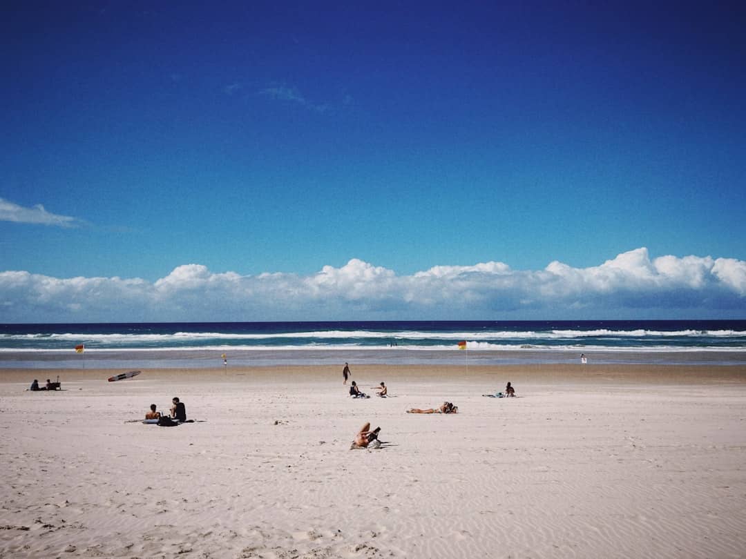 A group of people sitting on top of a sandy beach