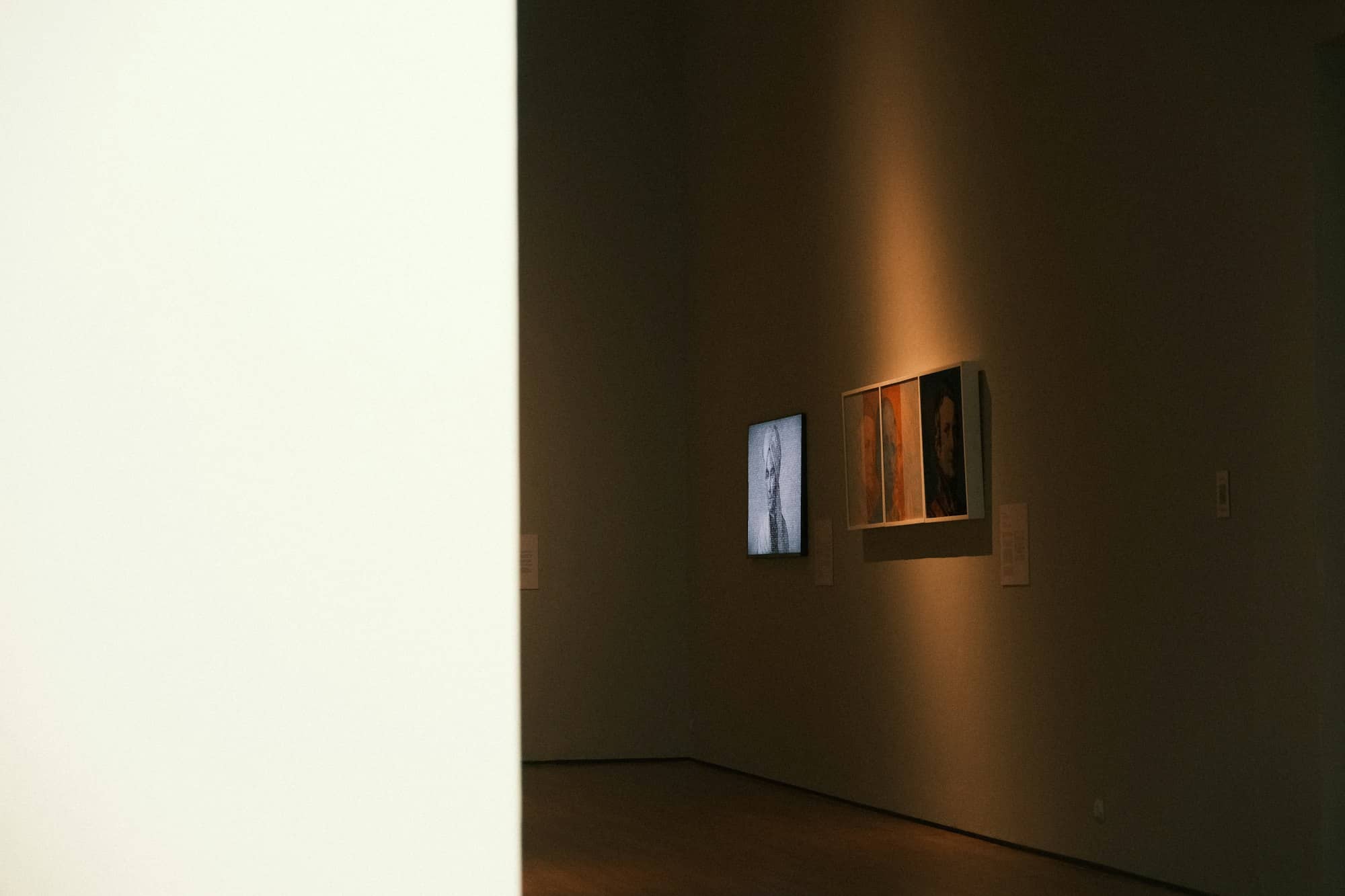 Two framed artworks illuminated by a spotlight.