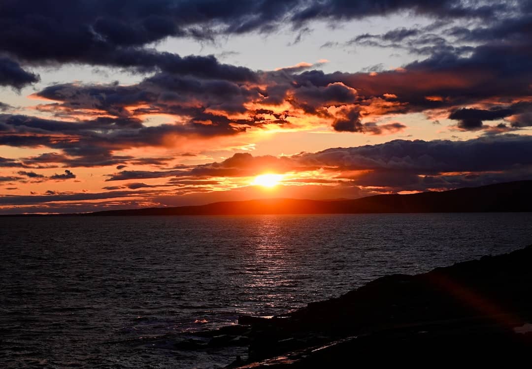 A sunset over a body of water with clouds in the sky