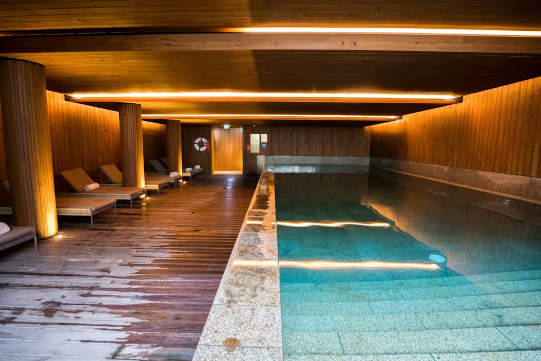 Indoor swimming pool with wooden walls and lounge chairs.