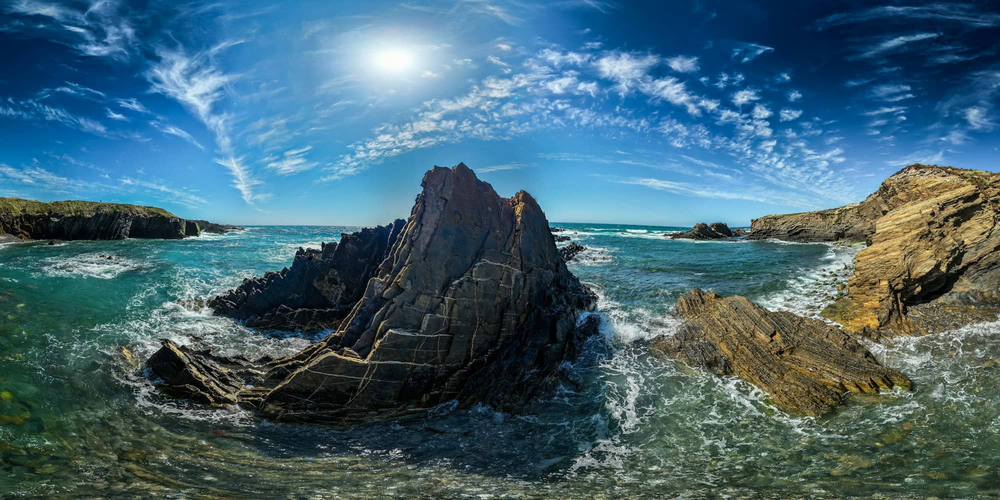 Jagged rocks on a coastline with waves crashing.