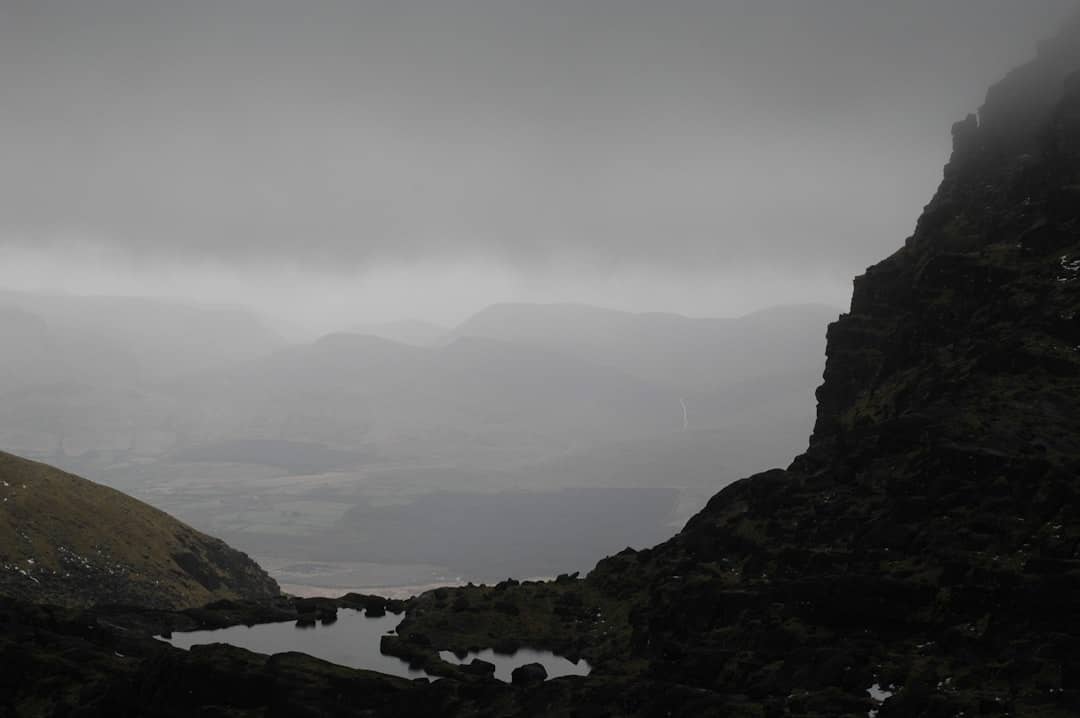a foggy mountain landscape with a lake in the foreground