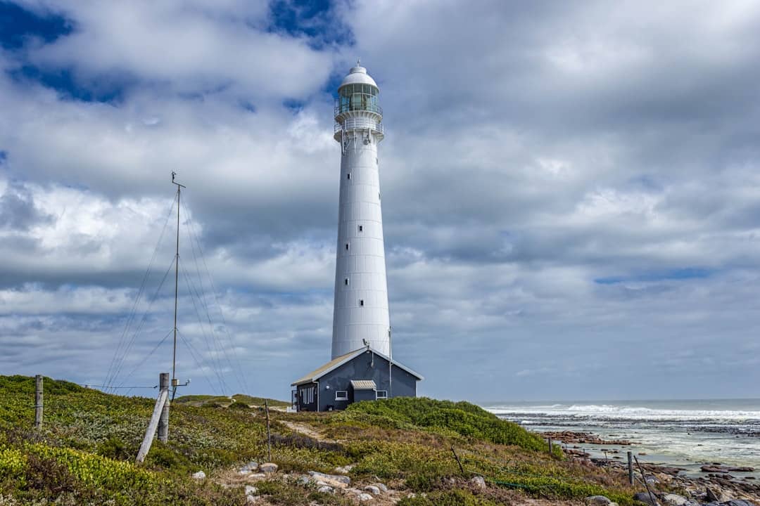 a light house on a grassy hill near the ocean