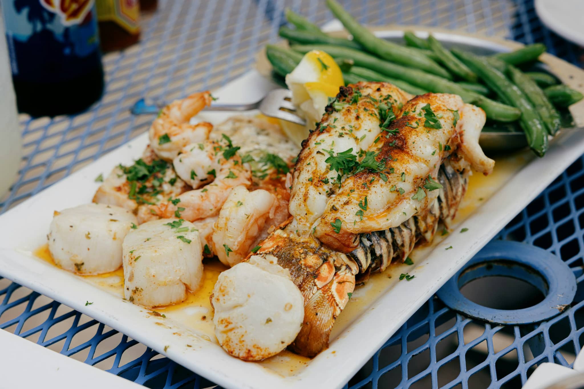A plate of lobster, shrimp, scallops and green beans
