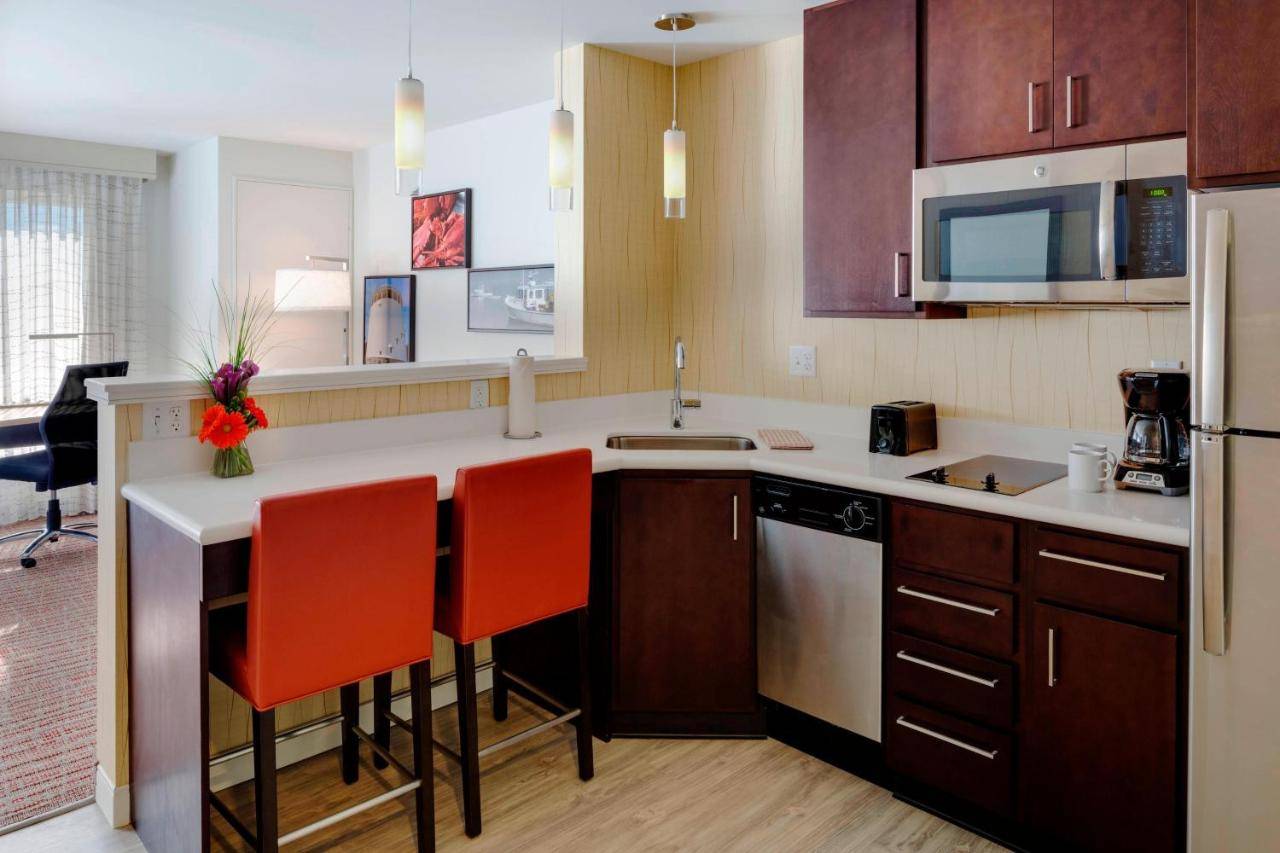 a kitchen with a counter and two red chairs at Residence Inn by Marriott Bangor in Bangor