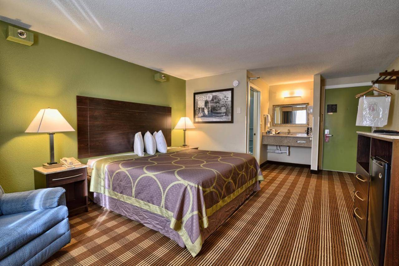a hotel room with a bed and a couch at Super 8 by Wyndham Bangor in Bangor