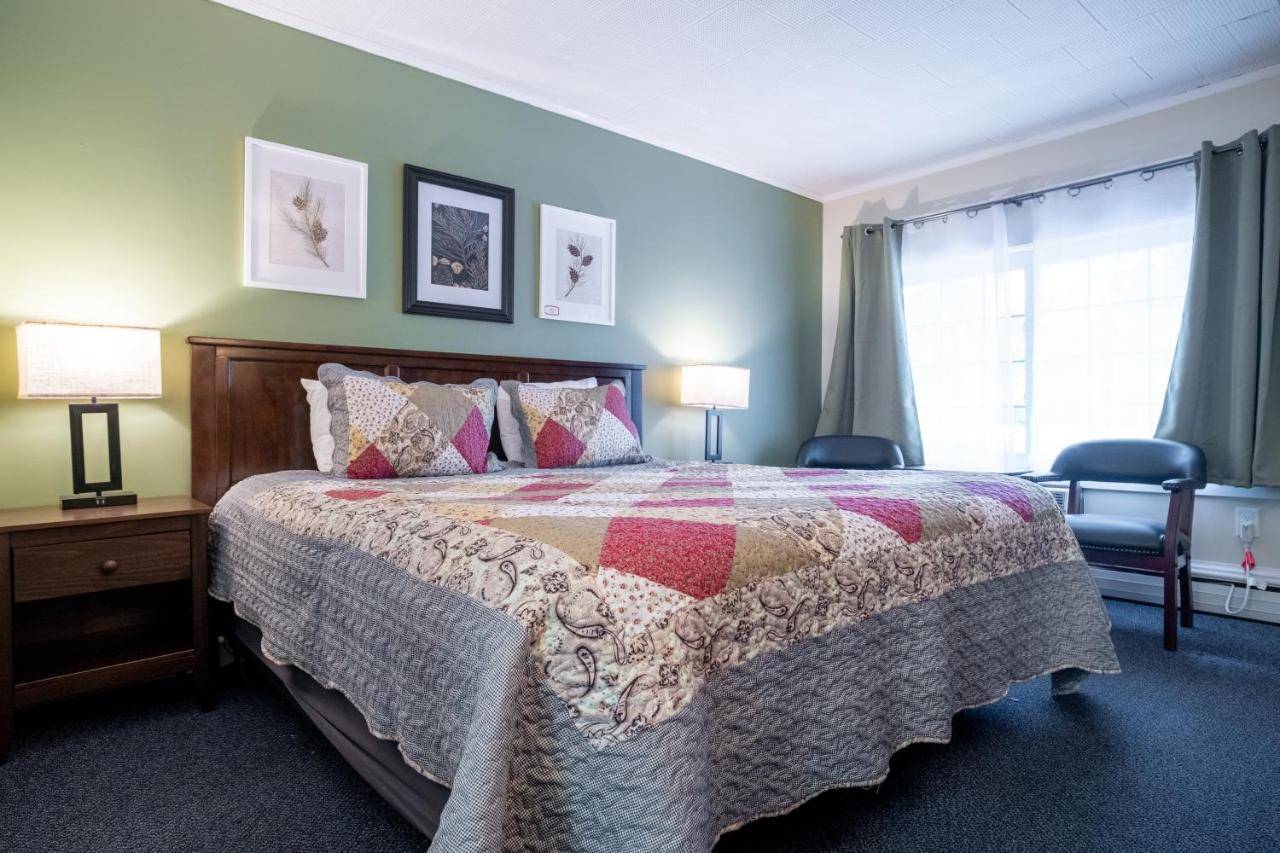 a bedroom with a bed and two lamps and a window at Acadia Pines Motel in Bar Harbor