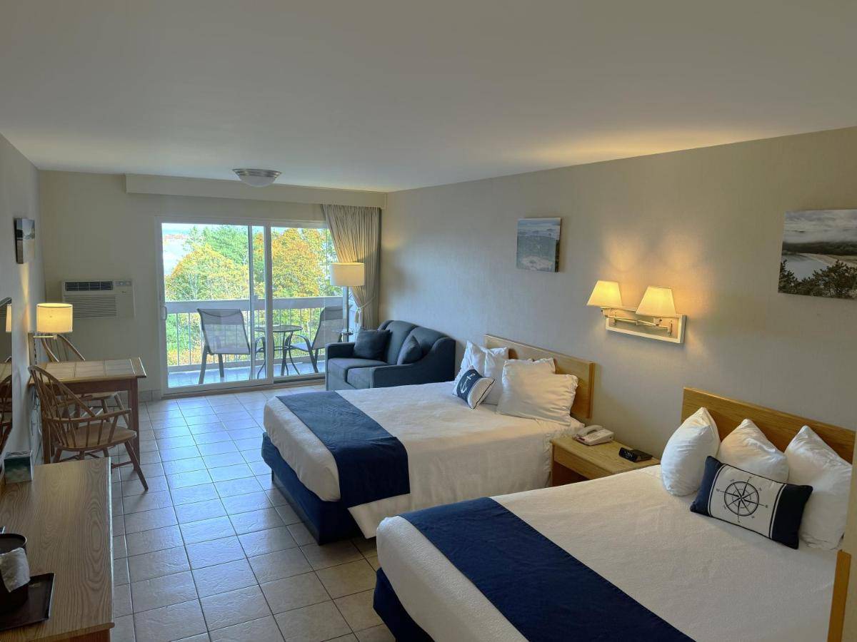 a hotel room with two beds and a balcony at Atlantic Eyrie Lodge in Bar Harbor