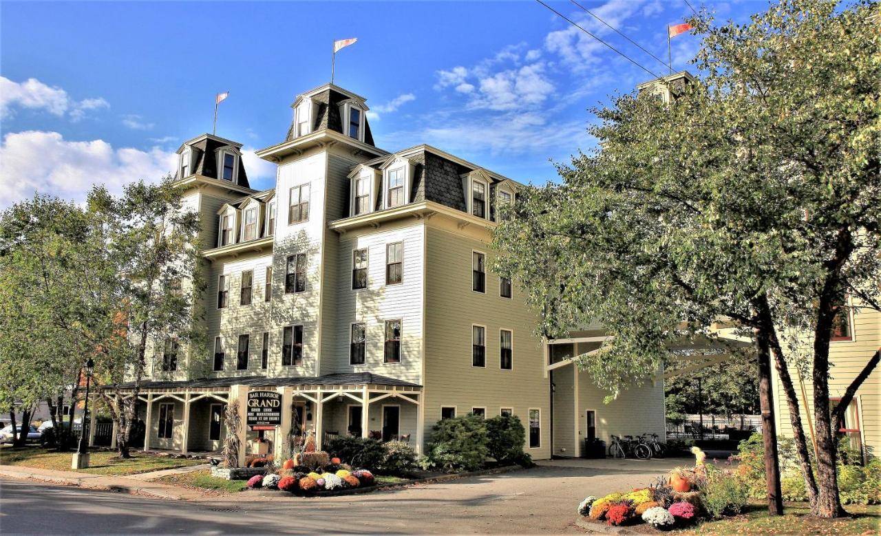 a large yellow and white building on a street at Bar Harbor Grand Hotel in Bar Harbor