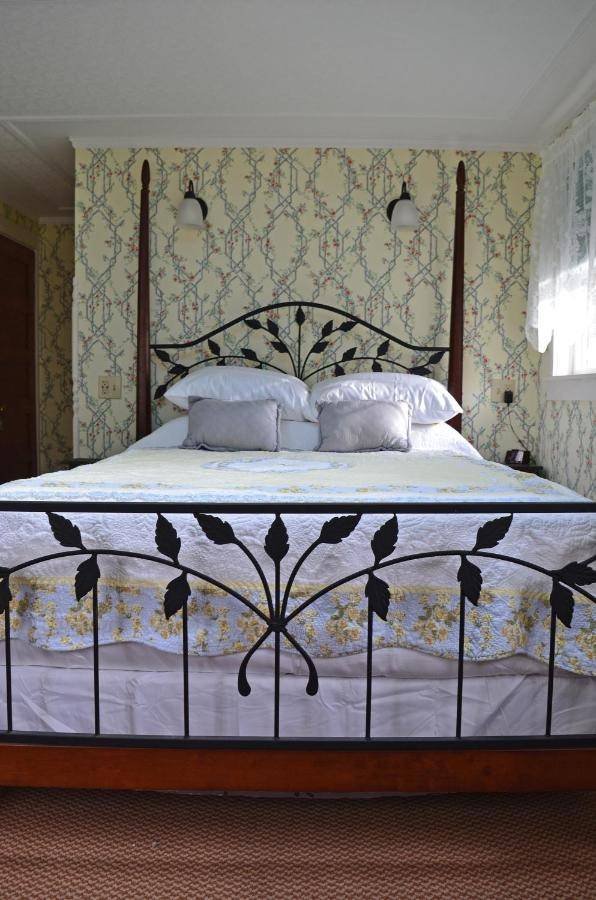 a bedroom with a large bed with white sheets and pillows at Black Friar Inn and Pub in Bar Harbor