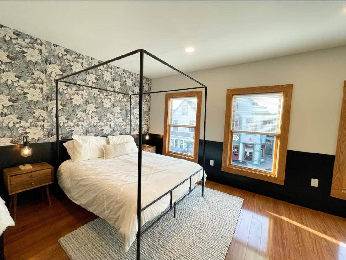 a bedroom with a canopy bed and a window at Cottage Street Downtown New Apartment in Bar Harbor