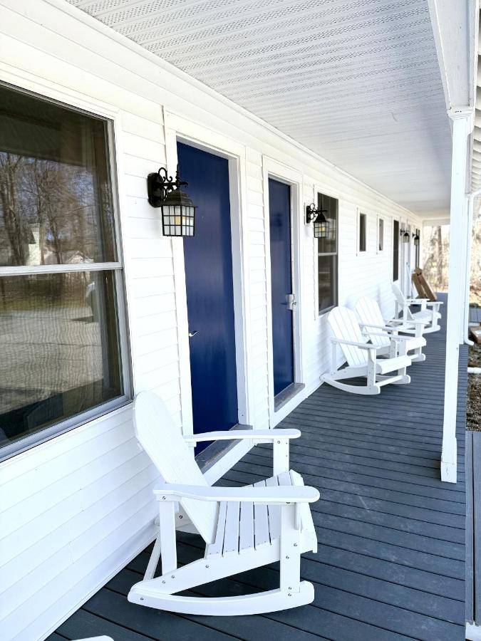 a porch with white rocking chairs on a white house at Eden Village Motel and Cottages in Bar Harbor