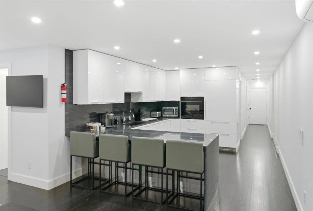 a kitchen with white walls and a bar with green chairs at Heart of Bar Harbor Steps to Shops & Dining in Bar Harbor