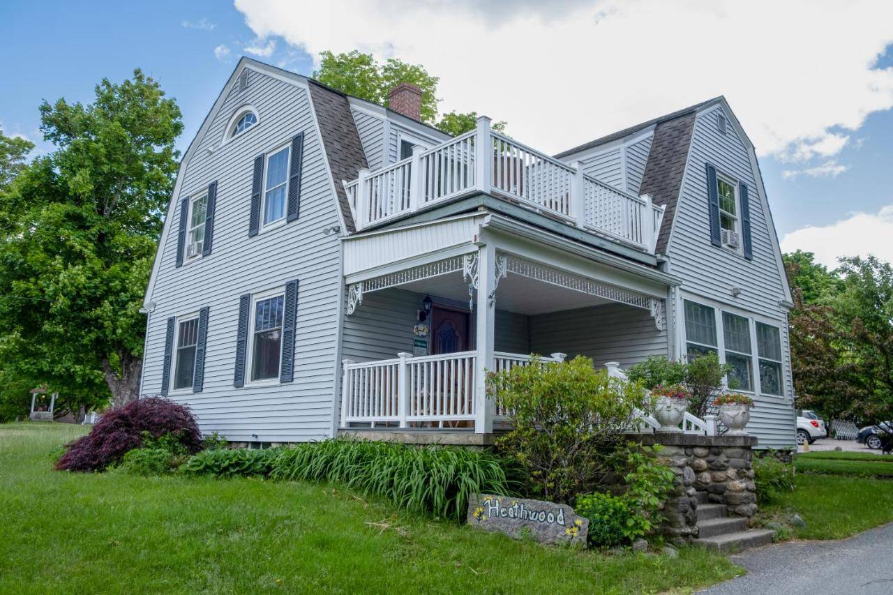 a white house with a porch and a balcony at Heathwood Inn in Bar Harbor