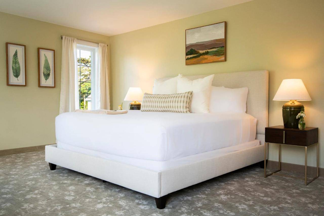 a large white bed in a room with a window at The Pathmaker Hotel in Bar Harbor