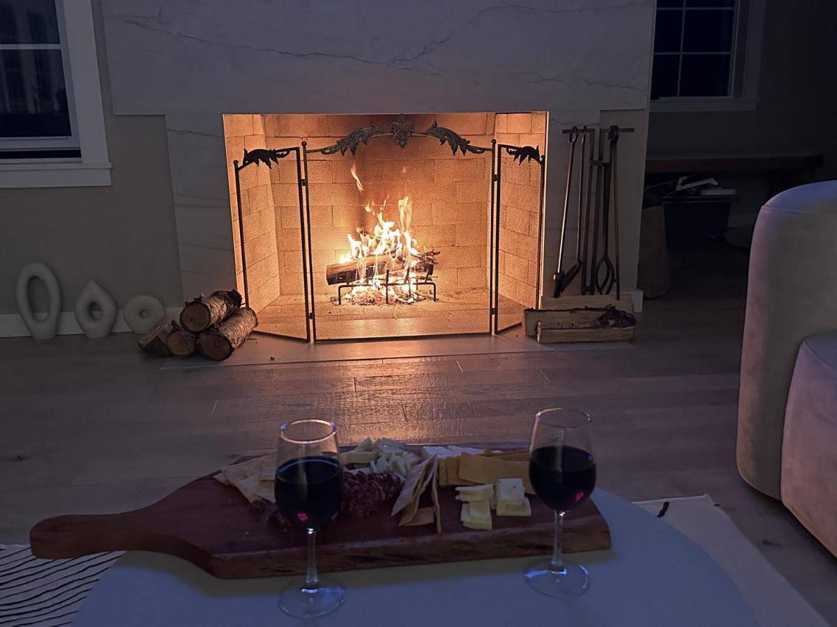 two glasses of wine on a table in front of a fireplace at Deluxe vc home 3 bd/2bath, whealchair accessible in Bass Harbor