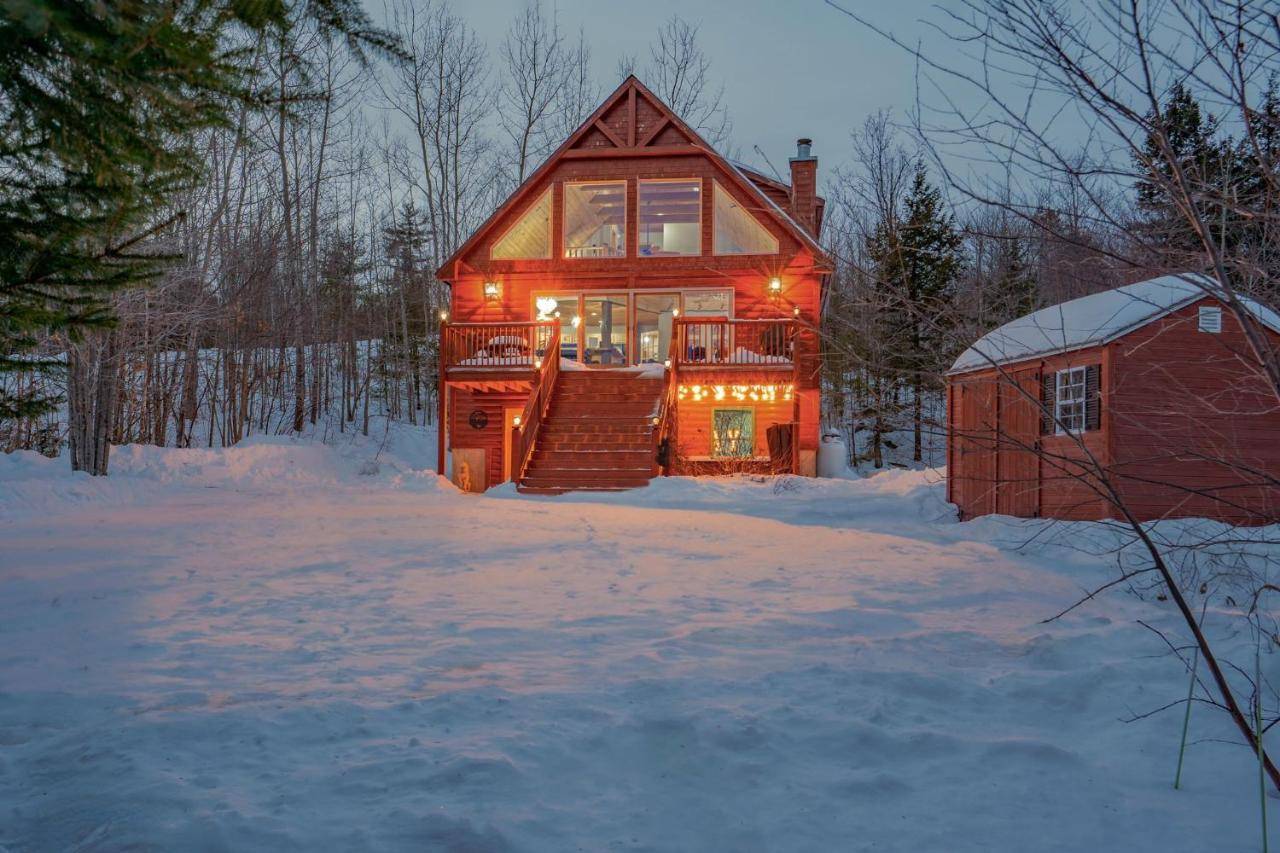 a home in the snow with lights on at 35 Hideaway - Mtn Views, Hot Tub, Game Room, Dogs Ok, 12 Mins to Sunday River in Bethel