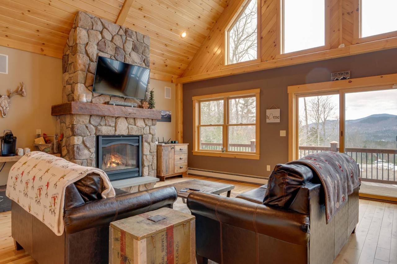 a living room with a stone fireplace and a tv at Spacious Cabin 10 Mi to Sunday River Skiing! in Bethel