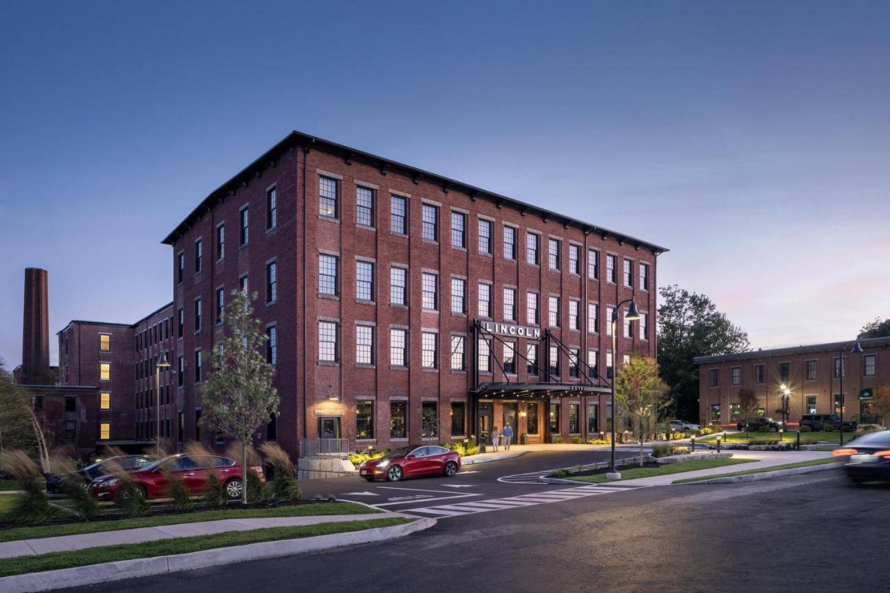 a large brick building with cars parked in front of it at The Lincoln Hotel in Biddeford