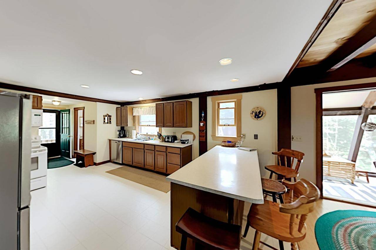 a kitchen with wooden cabinets and a counter top at Appalachee Pond Waterfront Cottage in Boothbay Harbor