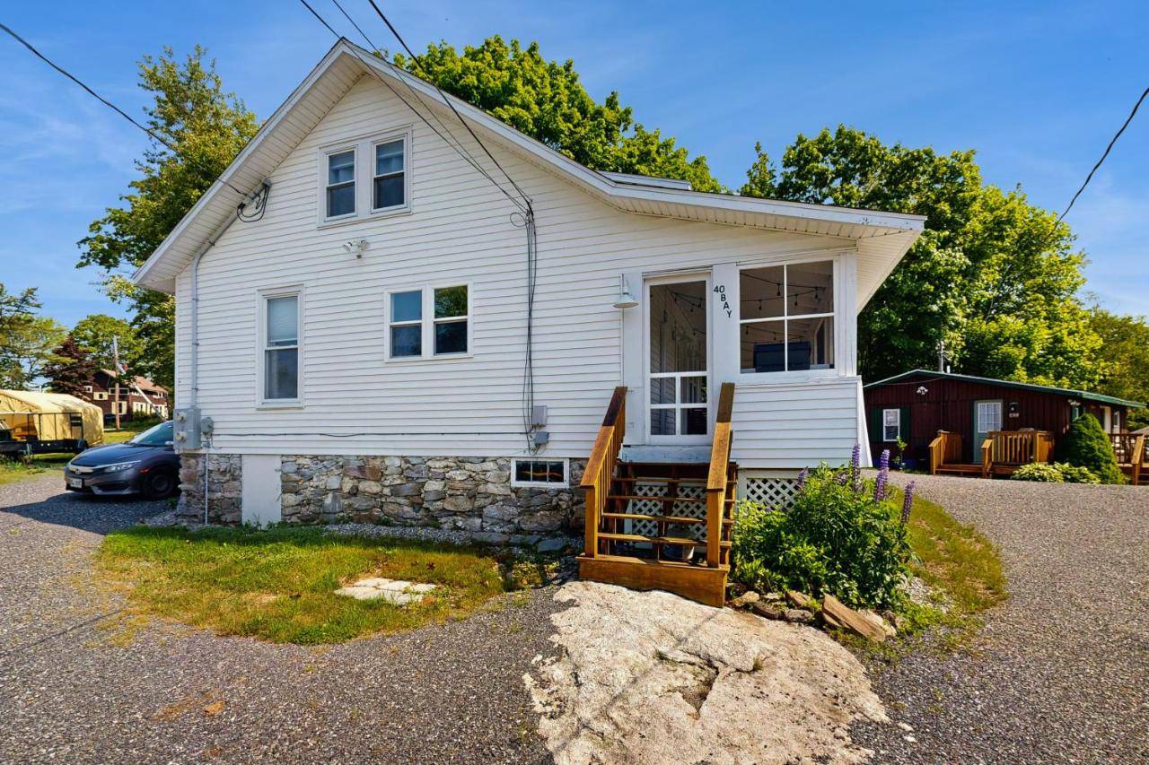 a white house with a porch and a driveway at Bay Cottage in Boothbay Harbor