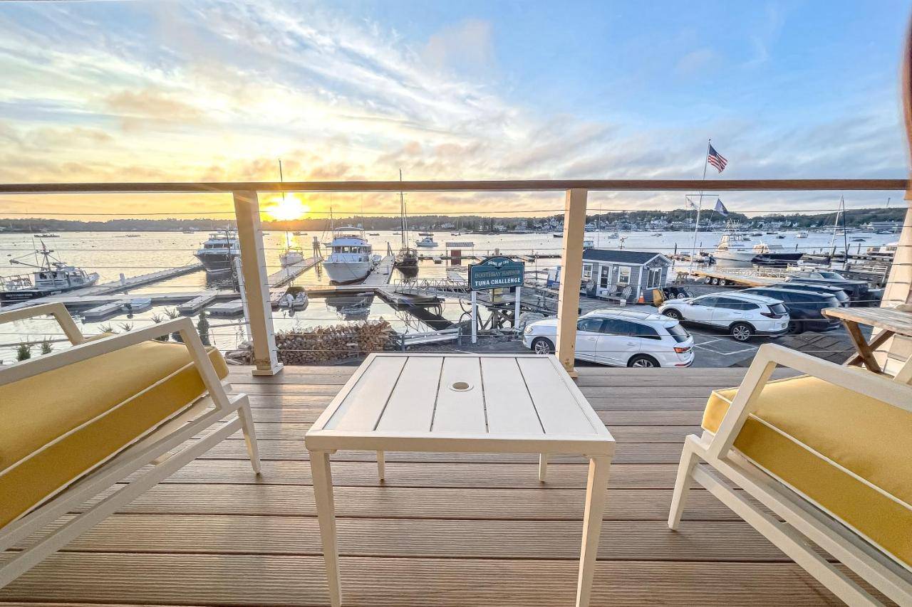 a balcony with a white table and a view of a marina at Ocean Breeze Condo in Boothbay Harbor