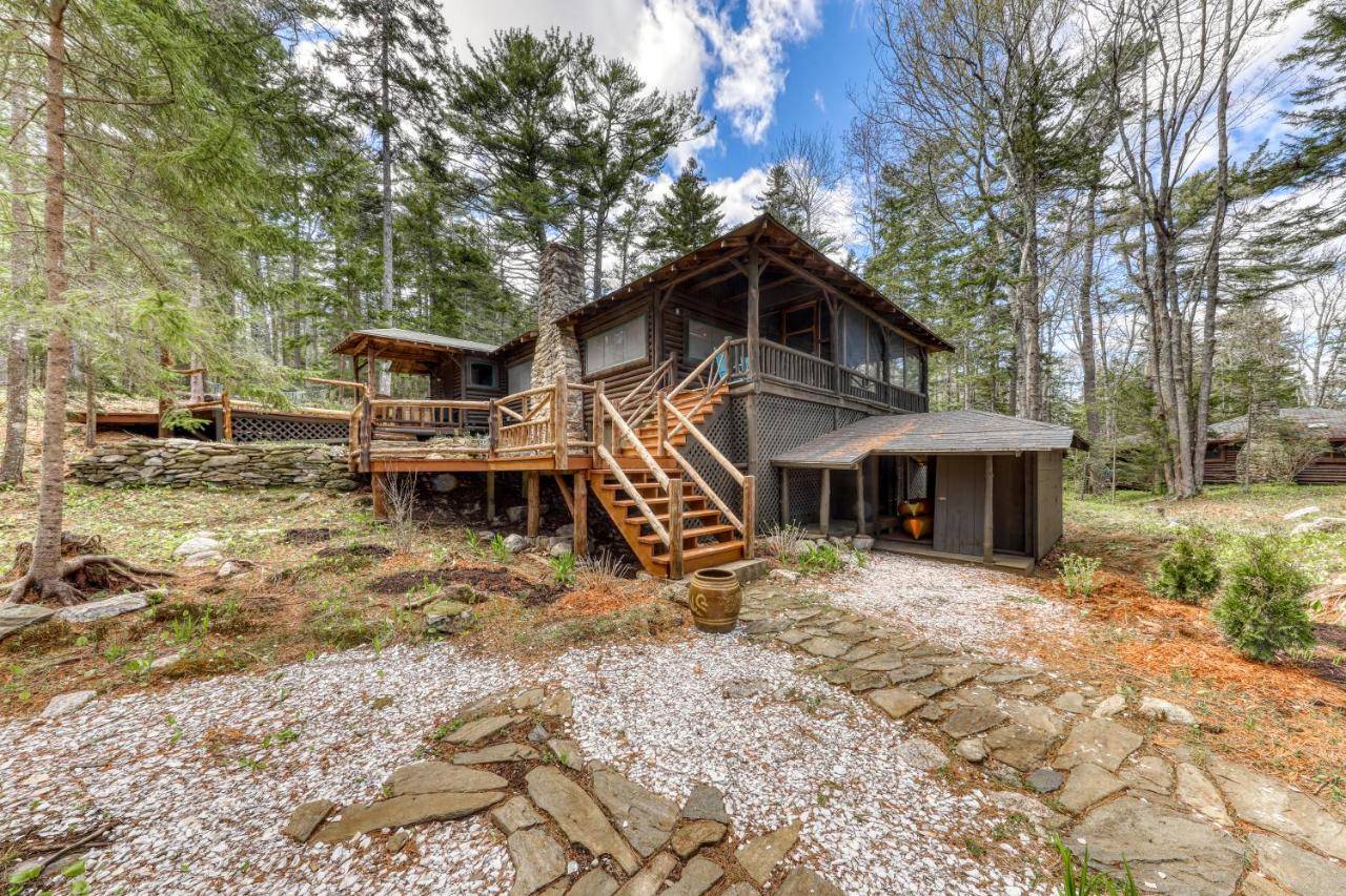 a log cabin in the woods with a porch and a deck at Sasanoa Retreat at Sprucewold in Boothbay Harbor