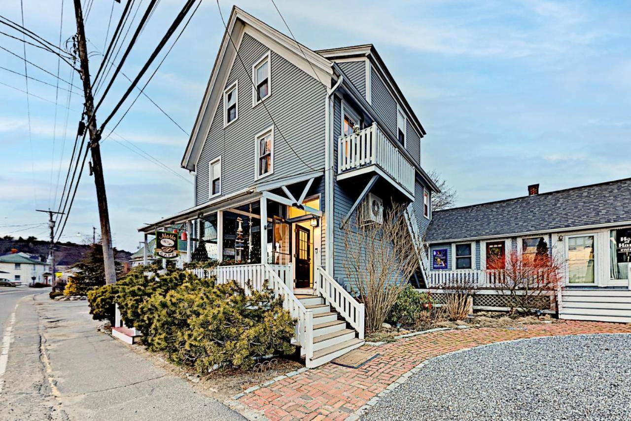 a gray house with a porch and stairs on a street at Snug Harbor Grande in Boothbay Harbor