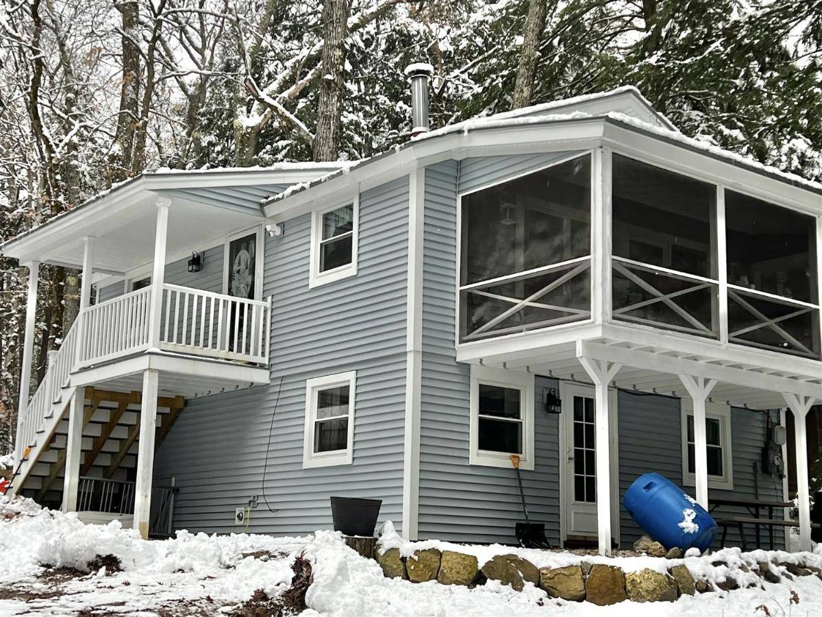 a house in the snow with a large porch at ANY SEASON ESCAPE LIMIT 10 villa in Bridgton