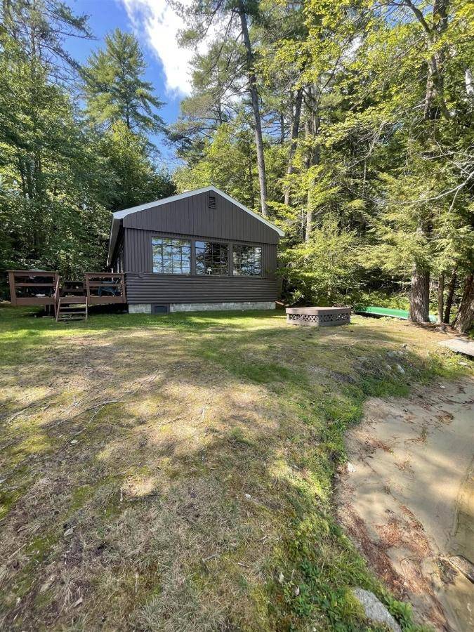 a black house in the middle of a yard at HIGHLAND HOLIDAY LIMIT 7-10 cottage in Bridgton