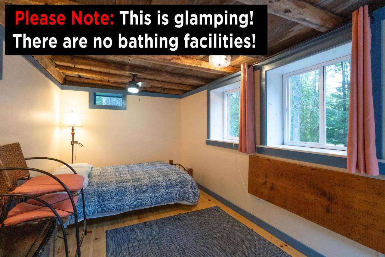 a bedroom with a bed and two windows at The ShackHilton at Dancing Light Farm in Bridgton