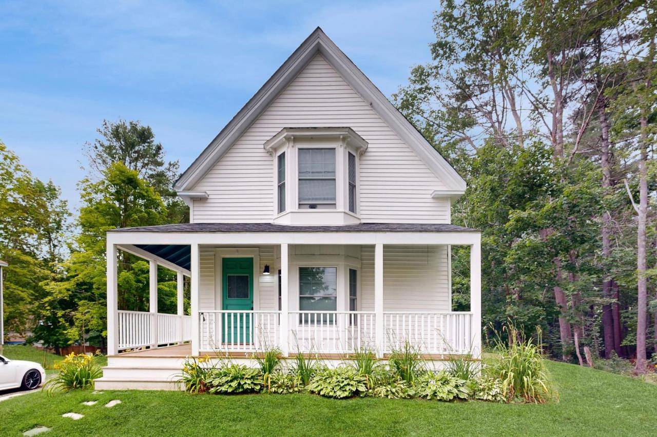 a white house with a porch and a lawn at Spring Pearl in Camden