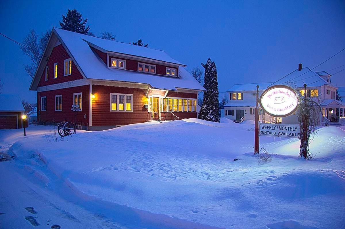 a house with a clock in the snow at night at Old Iron Inn Bed and Breakfast in Caribou