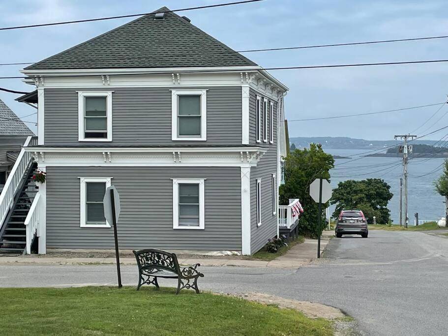 a bench sitting in the grass in front of a house at Updated Historic Water St 2 Bdr, 2 Bath apartment. in Eastport