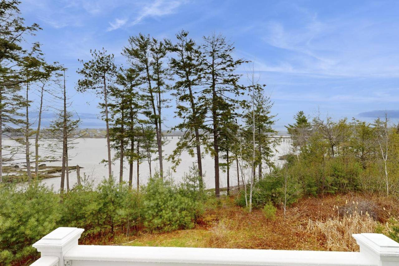 a white fence with trees and water in the background at The View at Sheepscot River in Edgecomb
