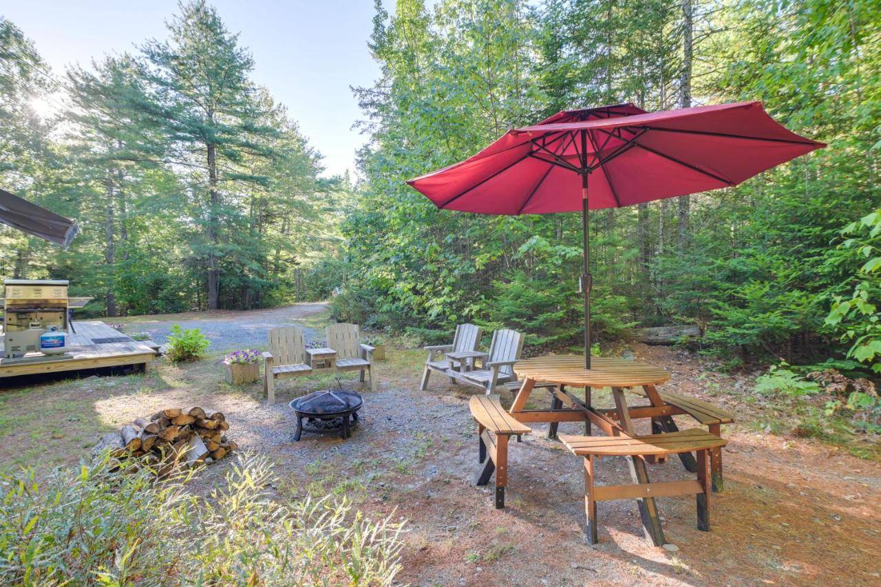 a picnic table with a red umbrella and chairs at 17 Mi to Acadia Cottage Near Downtown Ellsworth! in Ellsworth