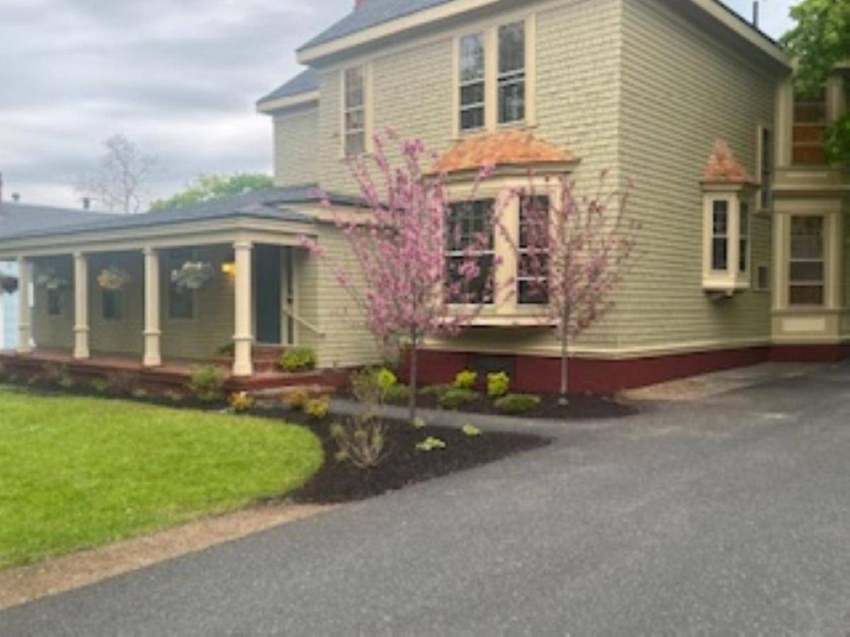 a green house with a yard with a driveway at 210 Main St in Ellsworth