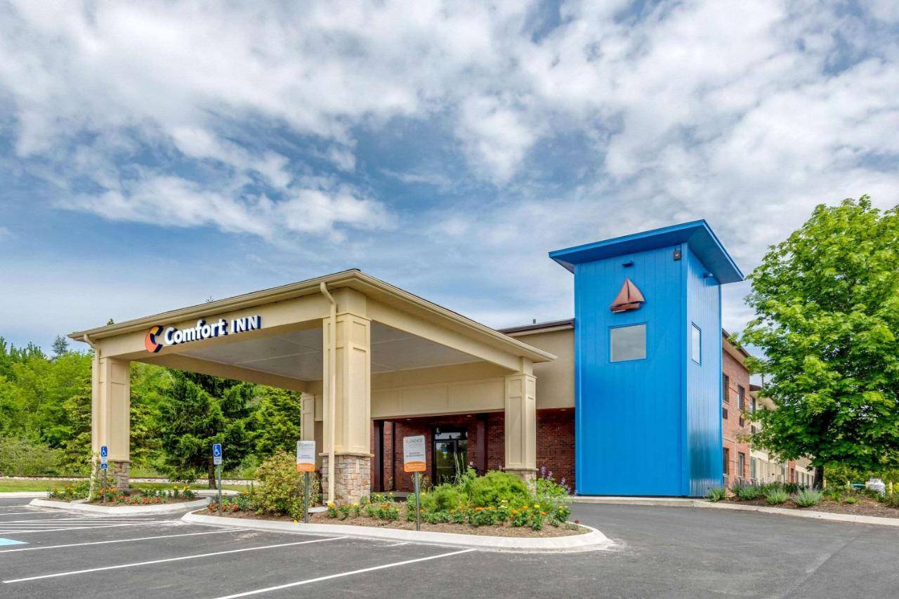 a car dealership with a blue building in a parking lot at Comfort Inn Ellsworth - Bar Harbor in Ellsworth
