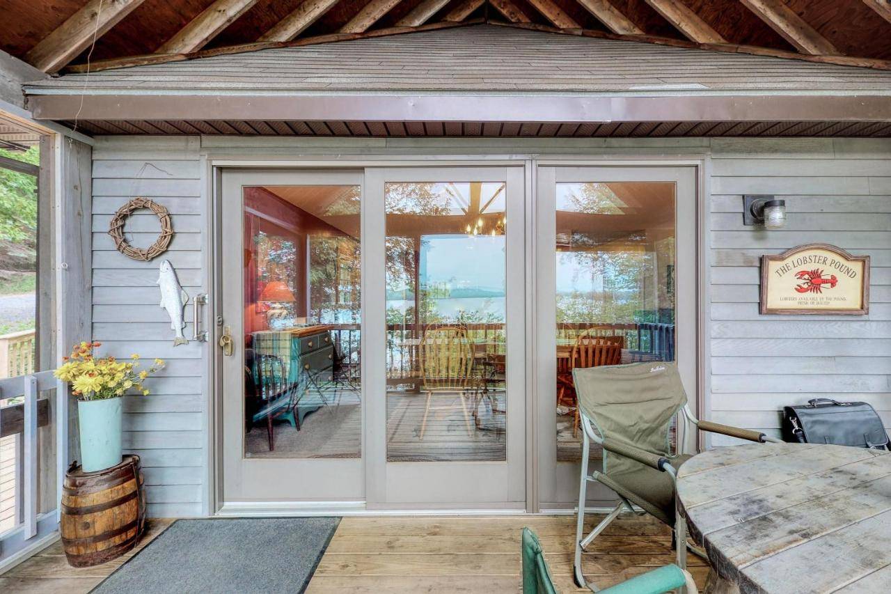 a screened in porch with a table and chairs at Loon Cove Cottage in Ellsworth