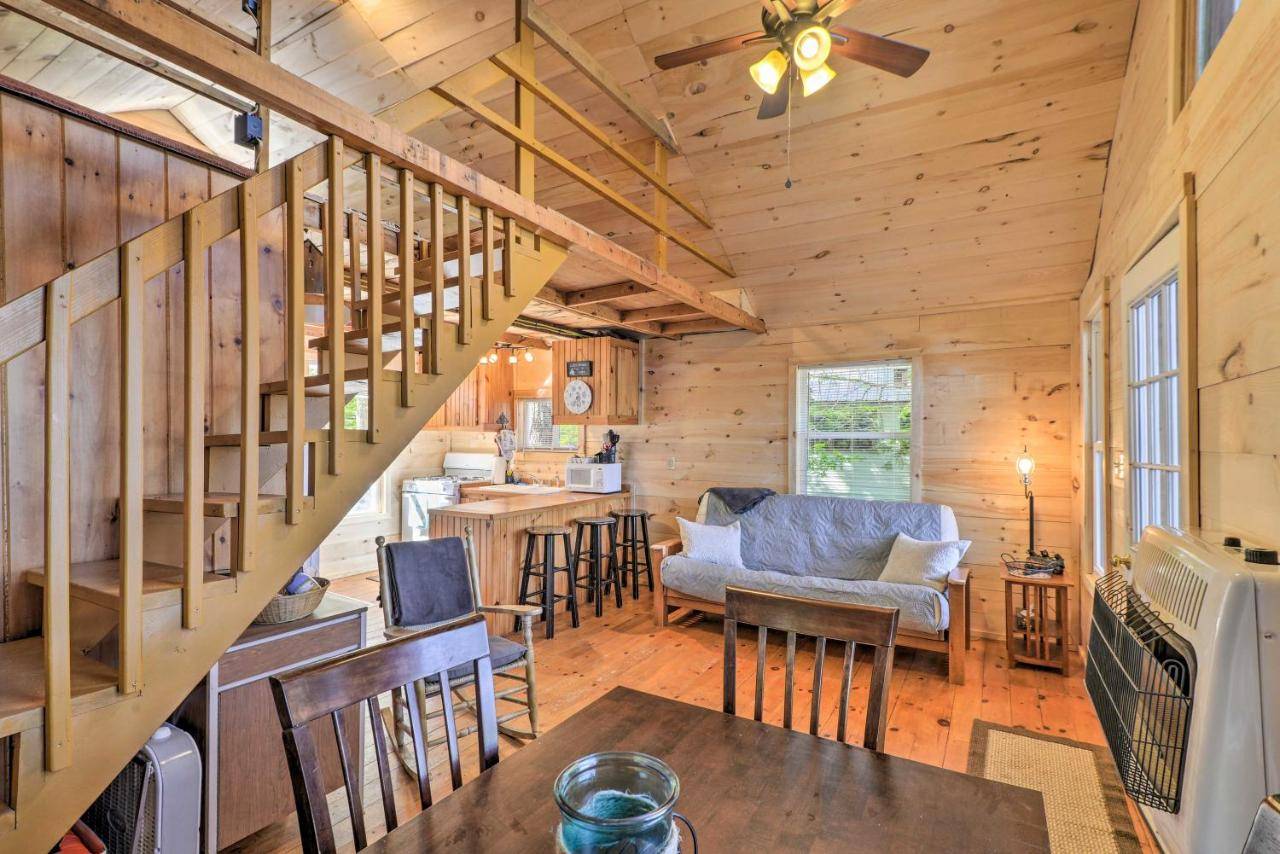a log cabin with a staircase and a living room at Pet-Friendly Ellsworth Cottage on Branch Lake in Ellsworth